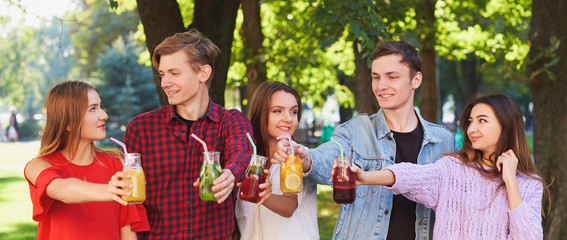Healthy nutrition. Group of friends drinking fresh juice detox on green nature background. Youth lifestyle, vegetarian diet to go, fitness food, successful weight loss concept