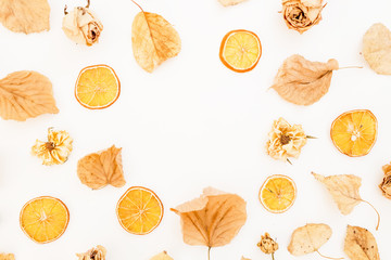 Fall concept of autumn leaves, dried roses and orange on white background. Flat lay, top view