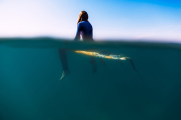 Surfer is sitting on surfboard in ocean. Surfer and ocean