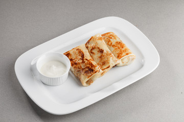 Pancakes with sour cream on a white plate