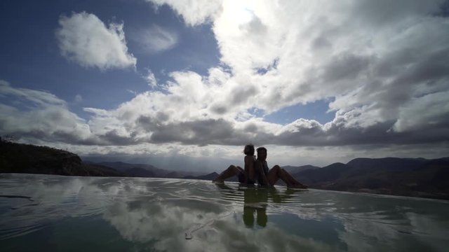 silhouette of young couple siting on the beautiful view in mineral pool,figure reflecting in water, Mexico Hierve el Agua