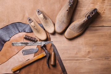 Cobbler tools in workshop on the wooden table . Top view.