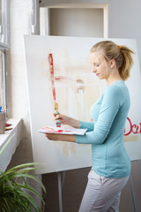 kreative junge frau malt in ihrem atelier