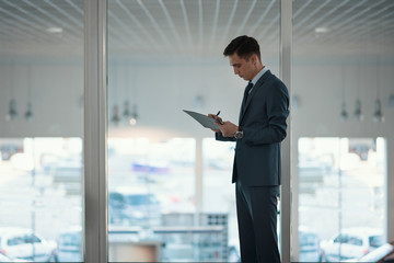 Fototapeta premium signing of agreement/ Businessman stands alone by the window in the office with a document and pen