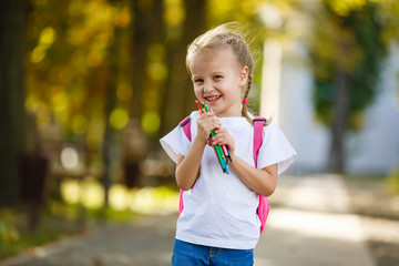 little schoolgirl with a backpack and pencils