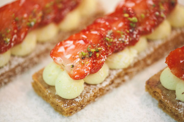 Deserts with strawberries and whipped cream decorated with pistachio crumble, close-up