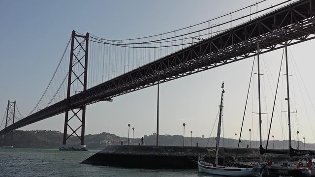 25 Abril Bridge Low Angle View Sailing In Tagus River. The 25 de Abril Bridge is a suspension bridge connecting the city of Lisbon to the municipality of Almada.
