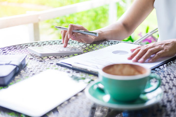 Business women working by using calculator for process financial report in the garden, outdoor workplace concept.