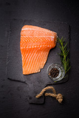 Raw salmon filet on dark slate background