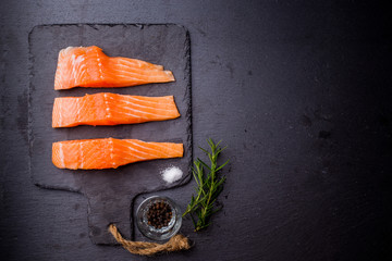 Raw salmon filet on dark slate background