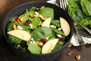 Spinach Apple salad served in a black bowl, selective focus