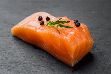 Raw salmon filet on dark slate background