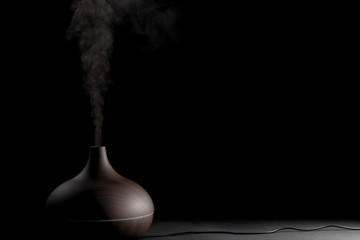 Electric aromatherapy device. Electronic diffuser gadget in use against black background. - obrazy, fototapety, plakaty