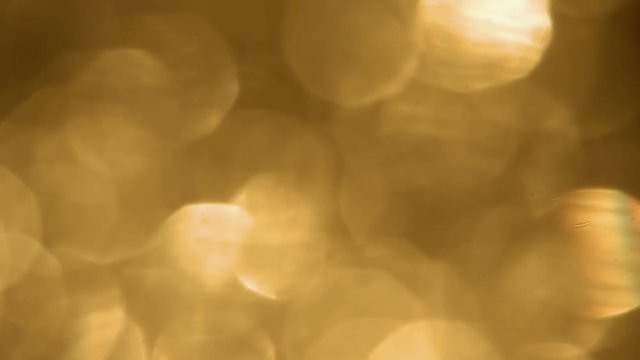 Fast moving shifting, sparkling, shimmering golden bokeh. This backdrop or compositing element is real, not CGI. High energy for high impact promos.