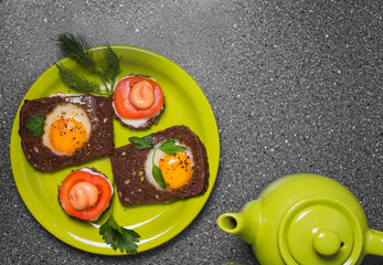 Breakfast -  toast with processed cheese tomato, fried eggs , fried eggs, teapot and cup of tea on a gray  background.