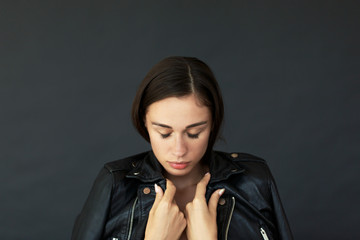 Naklejka premium Tender young woman envelopes herself in leather jacket