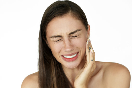 Woman holds fingers on her cheek showing toothache