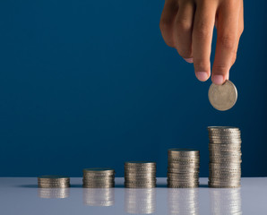 Hand holding coin on stacked of coins. Saving and investment concept