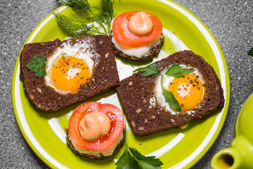 Breakfast -  toast with processed cheese tomato, fried eggs , fried eggs, teapot and cup of tea on a gray  background.