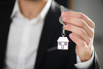 key chain with key in hand of a real estate agent