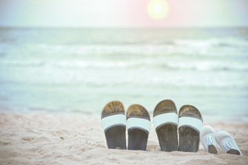 Slippers of the family on the beach and the sea as the background blurred.