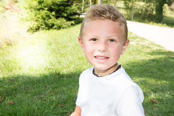 blond American boy smiling in the park during summer