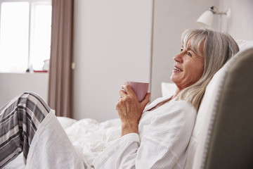 Senior Woman Relaxing In Bed With Hot Drink