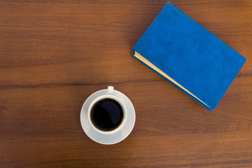 Obraz na płótnie Canvas Cup of coffee and closed book on wooden table