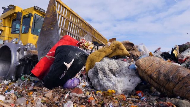 A landfill truck moving big and small garbage at landfill.