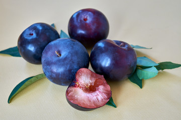 Group of plums with leaf on a yellow background.