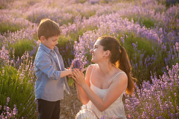 cute little son give bouquet of flowers to his happy beautiful mother