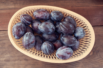 plum in a wicker basket on the wooden table