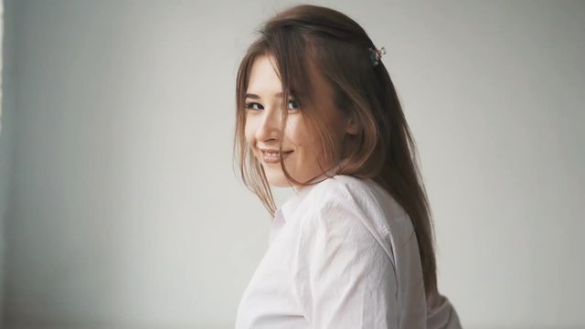 Dynamic scene of happy long hair girl, in casual shirt, walking while having fun in light white room