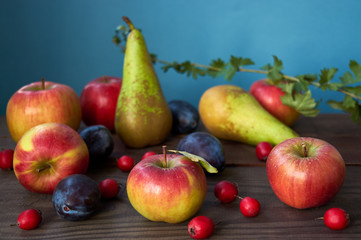 Autumn harvest. Pears, plums, apple, and leaves on the wooden table