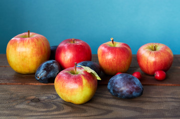 Autumn harvest. Plums, apple, and leaves on the wooden table