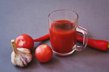 A glass of delicious tomato juice, fresh tomatoes of garlic and red pepper