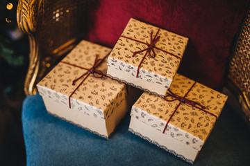 Wrapped gift boxes lie on armchair. Prepared surrpise on birthday or some other holiday. Horizontal picture of three present boxes with ribbons. Celebration and holiday concept.