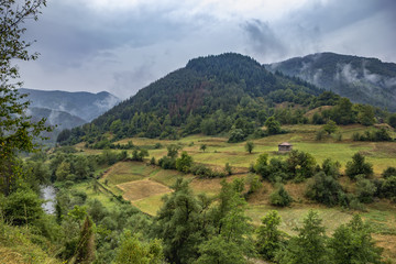 Obraz premium Summer mountain landscape after rain with mist , green meadows and rural house