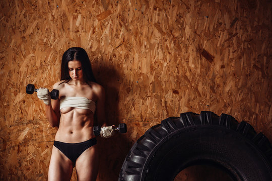 Sexy woman in black lingerue poses with barbells in the gym