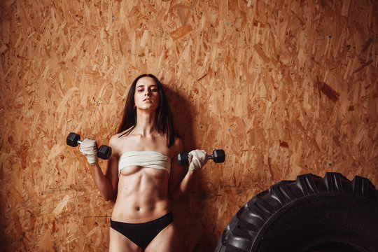 Sexy woman in black lingerue poses with barbells in the gym