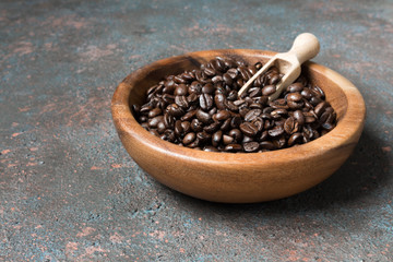 Coffee beans in a wooden bowl on a dark background with copy space in a minimalist style