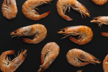 Shrimps on black background. Delicious seafood appetizer served boiled or grilled with spices. Close up. Top view