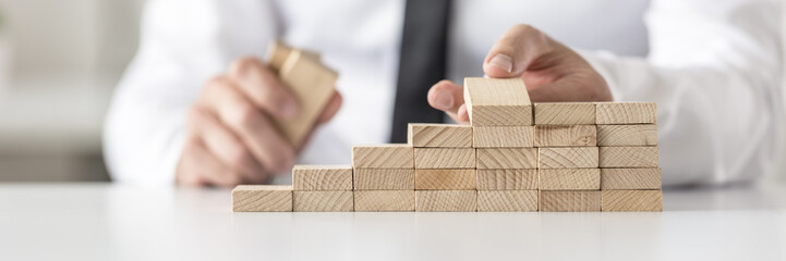 Closeup of businessman arranging wooden pegs into a staircase