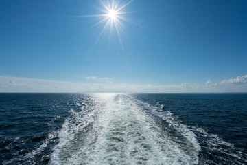 Sun shining over the wake of cruise ship at sea