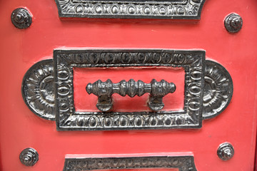 Poignée de porte en fer forgé noir sur bois rouge