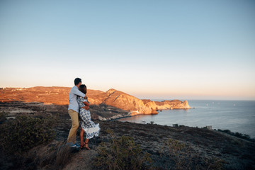 young happy couple at sunset hugging in rocky terrain