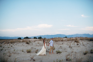 Fototapeta na wymiar beautiful couple walking holding hands on sand