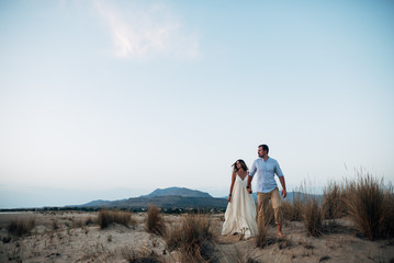 beautiful couple walking holding hands on sand