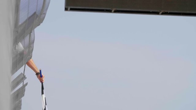 Man holding and waving Checkered race flag in slow motion at finish line on a raceway. Victory, achievement, success and sport concept.