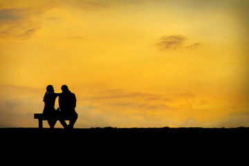 Back view of a couple silhouette sitting on Chair at colorful sunset on background